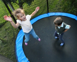 Two funny kids jumping on a outdoor trampoline.